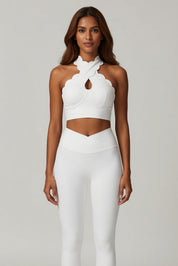 Woman wearing a white halter top and pants on a gray background